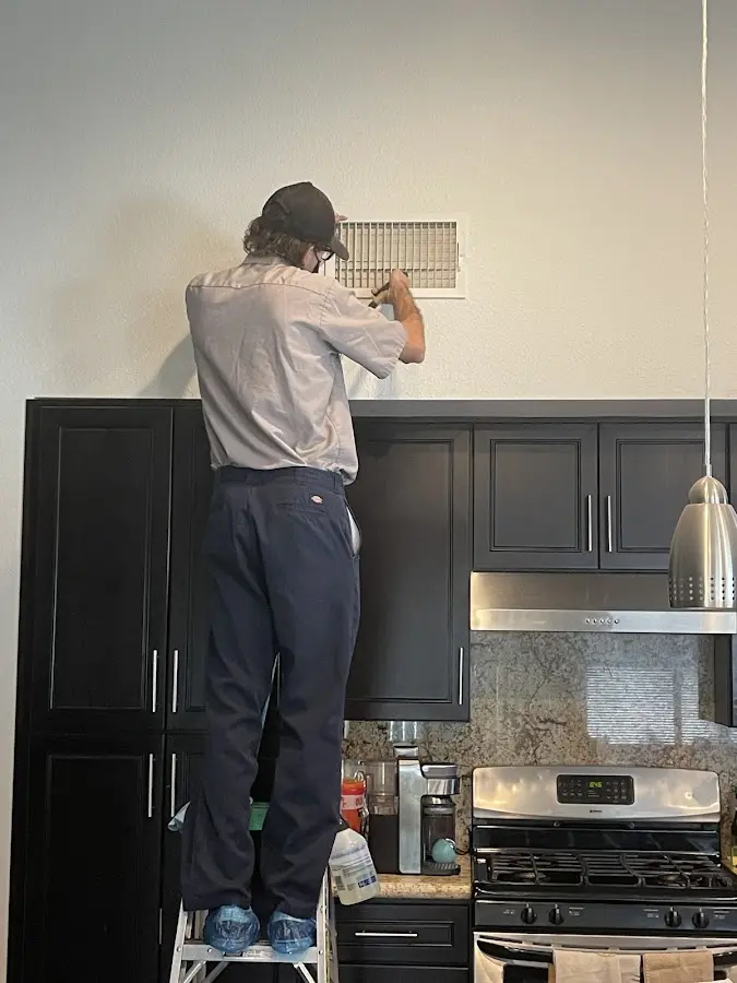 Technician inspecting an air vent during HVAC service in West Jefferson